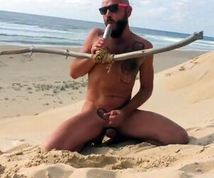 man humps himself on the beach with a wooden fake penis